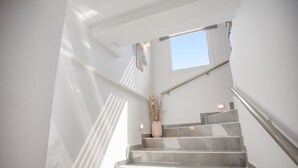 Eine Treppe mit Handlauf, einem Fenster und einer Vase mit Trockenpflanzen.