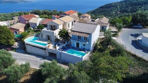 Eine Küstenvilla mit Schwimmbad, mehreren Balkonen und Meerblick.