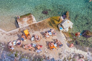 An aerial view of a beachside resort with clear waters, wooden deck, and sun loungers. - Casa Trenta Otto-J in Corfu (Corfu)
