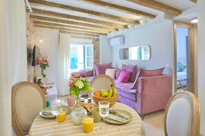 A dining area with a table set for breakfast, a sofa, and a mirror on the wall. - Casa Trenta Otto-J in Corfu (Corfu)