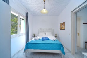 Un dormitorio con cama, ventana, puerta y un cuadro en la pared.