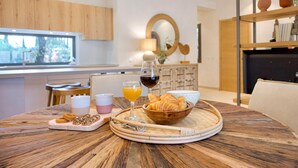 Une table en bois dressée pour le petit-déjeuner, avec des croissants, du jus d’orange et du vin.