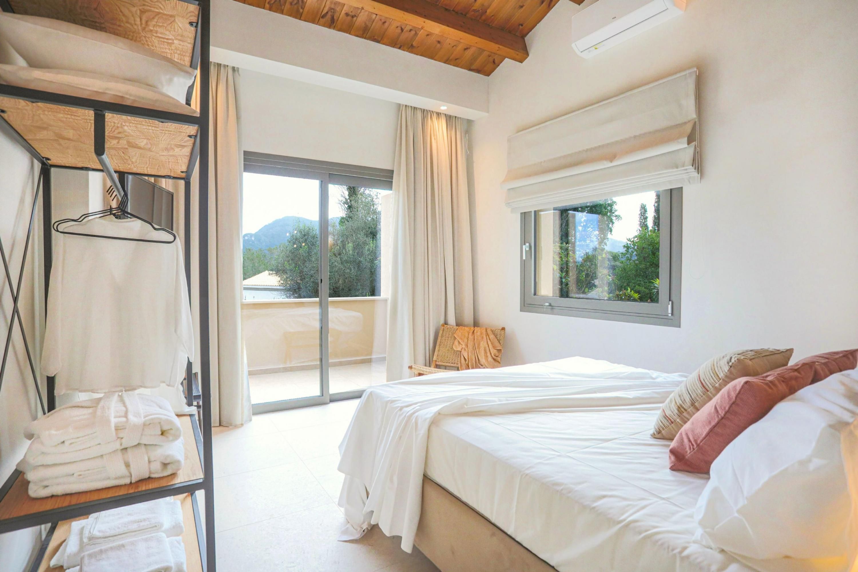 Ein Schlafzimmer mit einem großen Bett, einem Fenster mit Aussicht, einem Balkon und einem Regal mit Handtüchern.