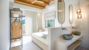 Une chambre moderne avec un lit, un plafond en bois, une armoire, une salle de bain avec un lavabo et des miroirs, et une fenêtre avec des rideaux.
