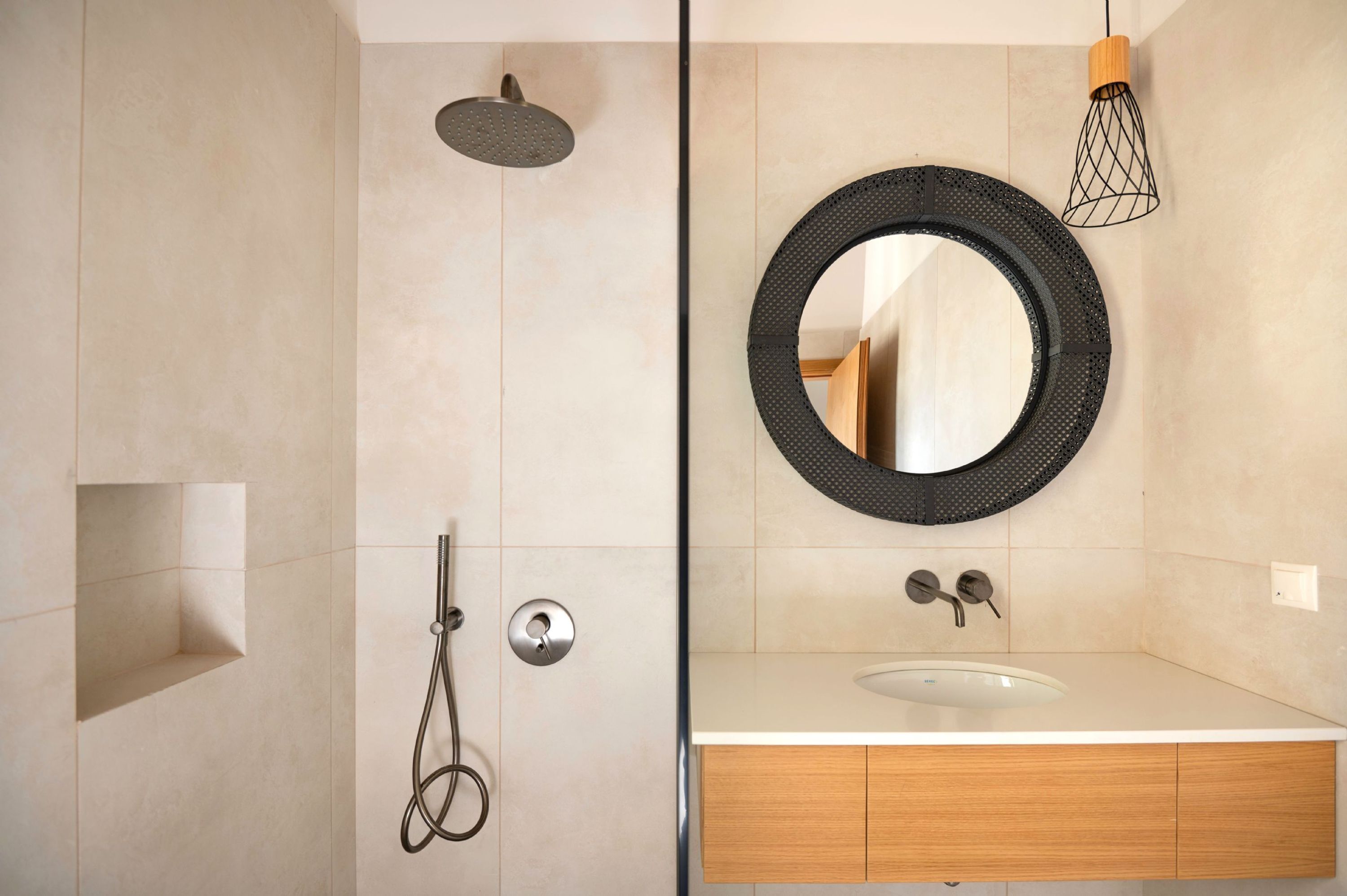 A modern bathroom with a shower, a round mirror, and a sink.