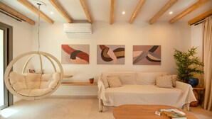 Een moderne woonkamer met een hangstoel, een bank, een houten salontafel en abstracte wanddecoratie.