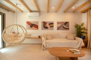 A modern living room with a hanging chair, a sofa, a wooden coffee table, and abstract wall art. - Residence Throubi in Ionian Islands (Ionian Islands)