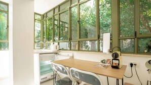 A small kitchen area with a table, chairs, a kettle, and a coffee maker. - Ben Yehouda Jonquille (Tel Aviv-Yafo)