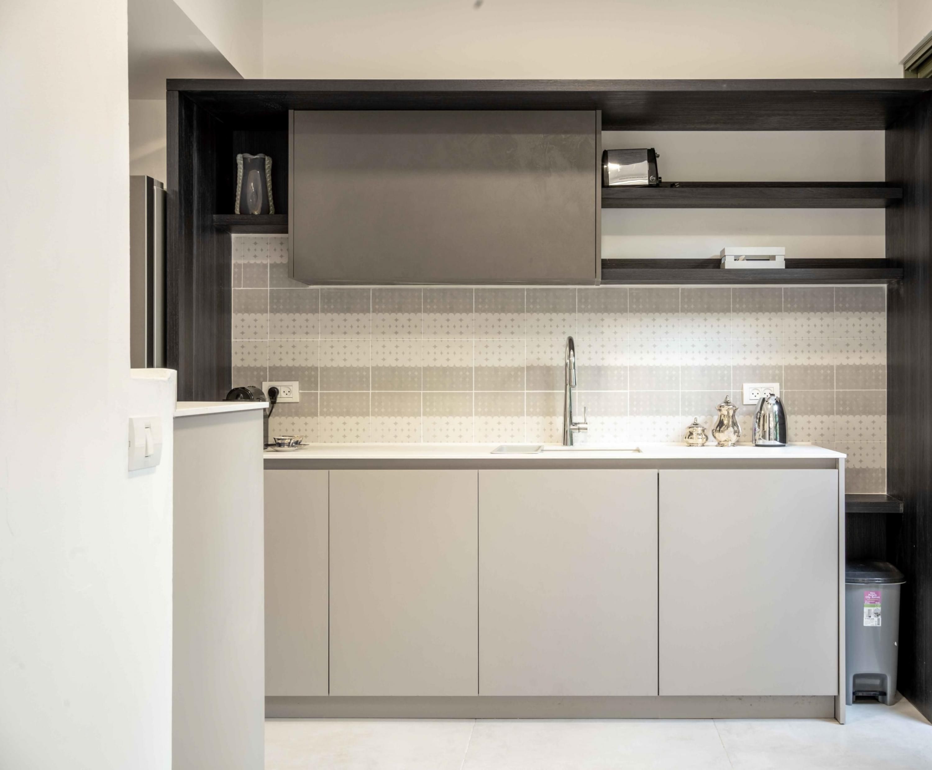 A modern kitchen with a central island, grey cabinets, and a tiled backsplash.