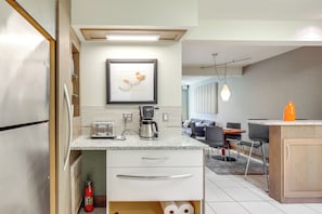 A modern kitchen with a stainless steel refrigerator, a coffee maker, and a framed artwork on the wall. - Water View! Walkable Gem Near Bayshore Boulevard (Tampa)