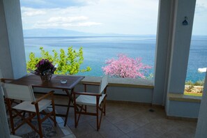 Ein Balkon mit Tisch und Stühlen mit Blick auf ein Gewässer und Berge.