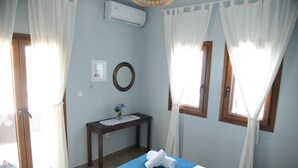 Un dormitorio con una cama, una mesita de noche con un florero y una ventana con cortinas.