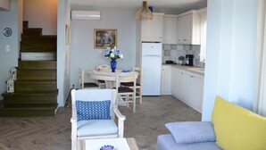 Een ruimtelijk ingerichte leefruimte met keuken, eethoek en een trap.