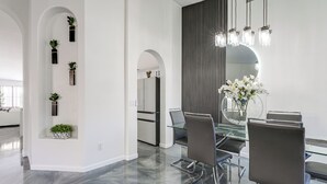Un espace repas moderne avec une table en verre, des chaises en métal et un grand miroir.