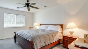 Een slaapkamer met een bed, nachtkastjes, een lamp, een plafondventilator en een raam met jaloezieën.