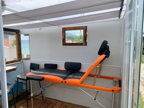 A room with a bed, a small table, and a window with a view of the sea. - Rooftop Loft with Hydromassage (Nees Pagases)