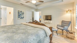 Un dormitorio con una cama, ventilador de techo, televisor, silla y lámpara.