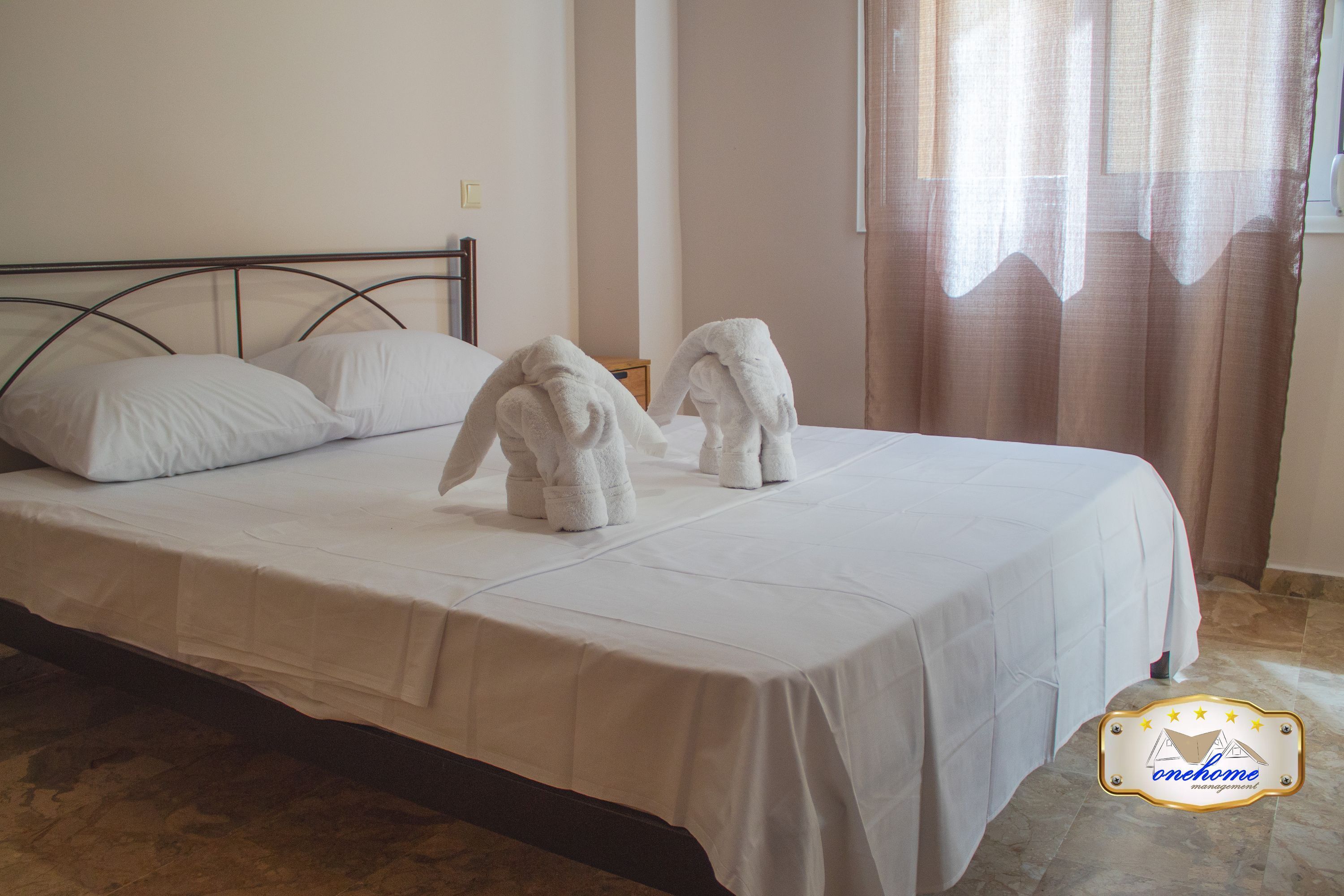 Un lit bien fait, avec du linge de lit blanc et deux serviettes posées dessus.