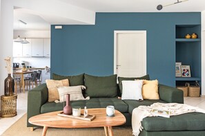 A modern living room with a green sofa, a wooden coffee table, and a white door. - Luxury house with Pool & Seaview - Infinite Blue (Ligaria)