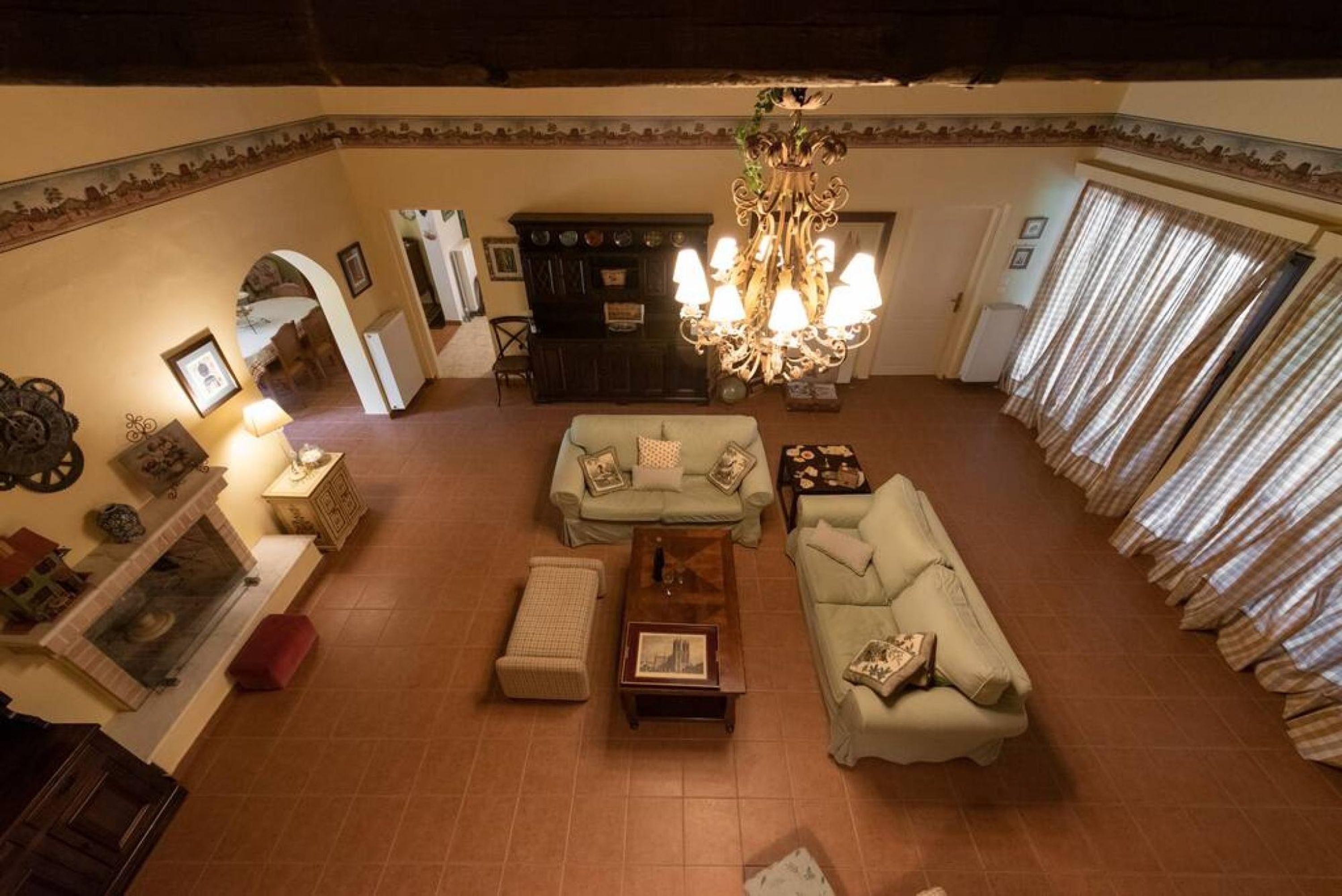A spacious living room with a fireplace, a chandelier, and a sofa set.