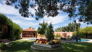 Un giardino con piscina, un tavolo con frutta e un edificio con tetto rosso.