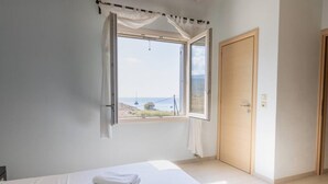 Ein Schlafzimmer mit großem Fenster, einem Bett und einer Tür.