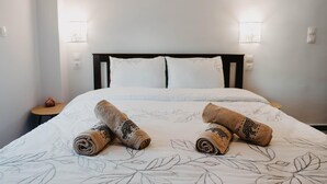 A neatly made bed with rolled towels and a floral-patterned bedspread. - Minimal Condo Trikala town (Trikala)