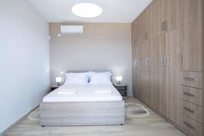 Ein Schlafzimmer mit Bett, Nachttischen, einer Klimaanlage und einem Holzschrank.