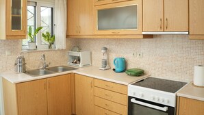 A kitchen with wooden cabinets, a sink, a stove, and a window with plants. - Nikis Country House - Lefkada BnB  Private Parking (Ligia)