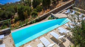 A swimming pool with lounge chairs, surrounded by greenery and overlooking a coastal area. - Branch Suite w Shared Pool by Roots Suites (Agios Nikolaos)