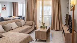 A modern living room with a sofa, a coffee table, and a TV stand. - Sky 7 View Apartment (Heraklion)