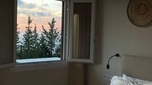 Ein Schlafzimmer mit Bett, einem Vorhangfenster, Deckenventilator und einer Wandleuchte.