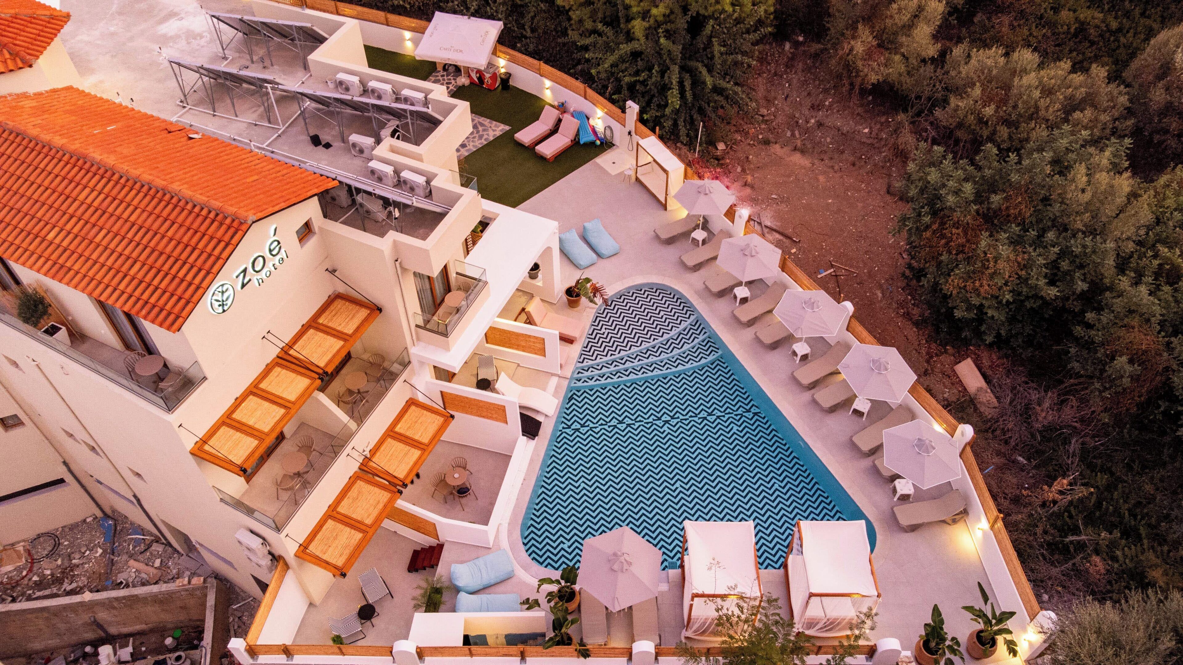 A rooftop pool area with lounge chairs, a swimming pool, and a terrace with a view of the surrounding forest.
