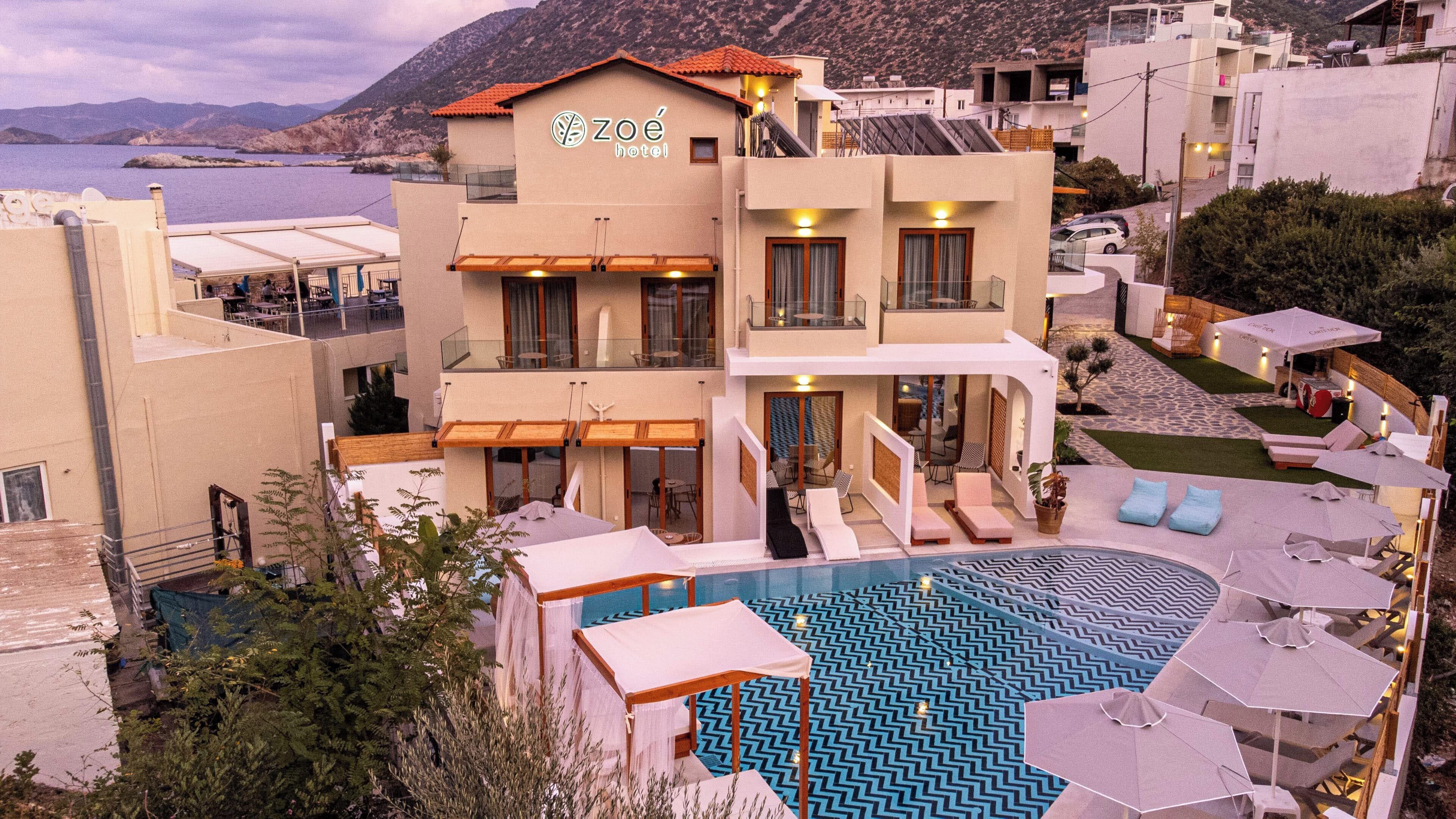 A hotel with a pool, outdoor seating, and a view of the sea.