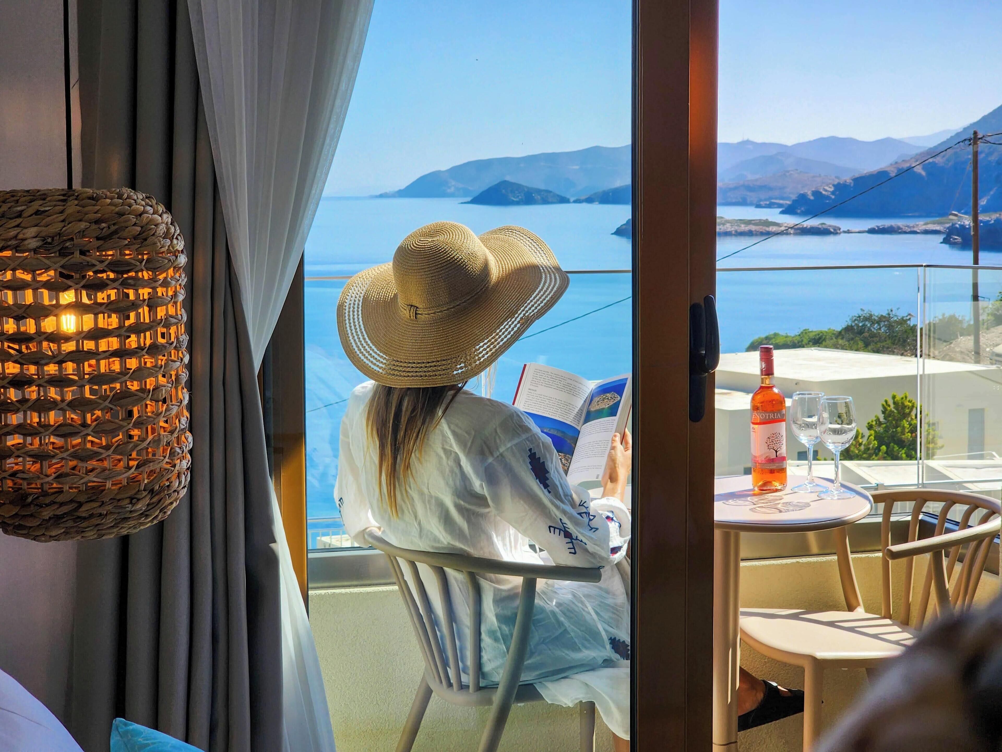 Une personne est assise à une table, devant un livre, et peut admirer un lac et des montagnes.