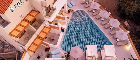 A hotel with a swimming pool, lounge chairs, and a terrace area.