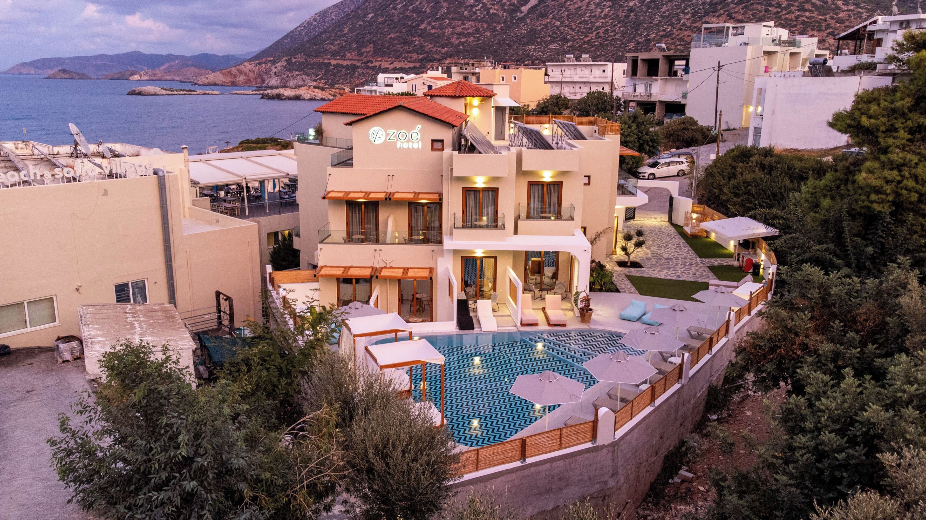 A modern hotel with a rooftop pool, multiple balconies, and a view of the sea.