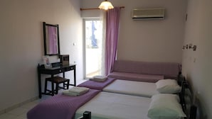 Ein Zimmer mit zwei Einzelbetten, einem Schreibtisch mit Stuhl, einem kleinen Tisch und einem Fenster mit Vorhängen.