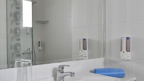A modern bathroom with a white sink, a large mirror, and a glass shower enclosure. - Apartment with Pool View (Ayia Napa)