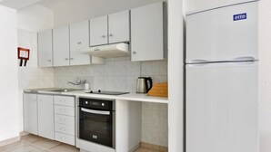 A modern kitchen with white cabinets, a built-in oven, a sink, and a refrigerator. - Apartment with Pool View (Ayia Napa)