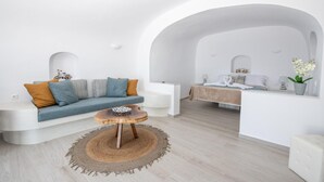 Uma sala de estar moderna com um sofá, uma mesa de centro e uma cama ao fundo.
