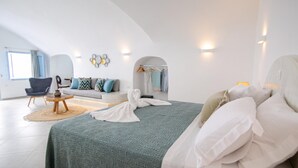 Quarto moderno com cama, sofá, poltrona e uma mesinha.