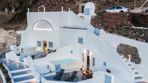 Um edifício branco com piscina, área de estar ao ar livre e escadaria.