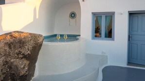 Un edificio blanco con estructura de piedra, una ventana circular y una puerta azul.