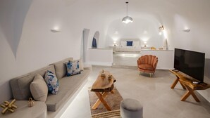 Una sala de estar moderna con sofá, reposapiés, mesa de centro, televisor y una silla.