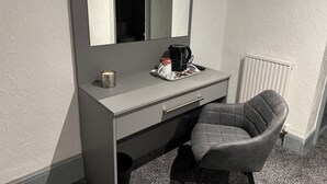 Une pièce de taille modeste, comprenant un bureau gris, une chaise, une machine à café et un petit plateau avec des en-cas.