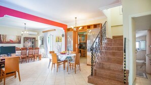 Un grand espace de vie comprenant une table à manger, des chaises, un escalier et un coin cuisine.