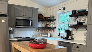 A kitchen with a wooden island, grey cabinets, a microwave, and a toaster. - Cozy cottage on the river and minutes from Dahlonega. (Dahlonega)