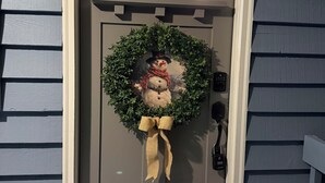 A gray front door with a wreath and a snowman decoration. - Cozy cottage on the river and minutes from Dahlonega. (Dahlonega)