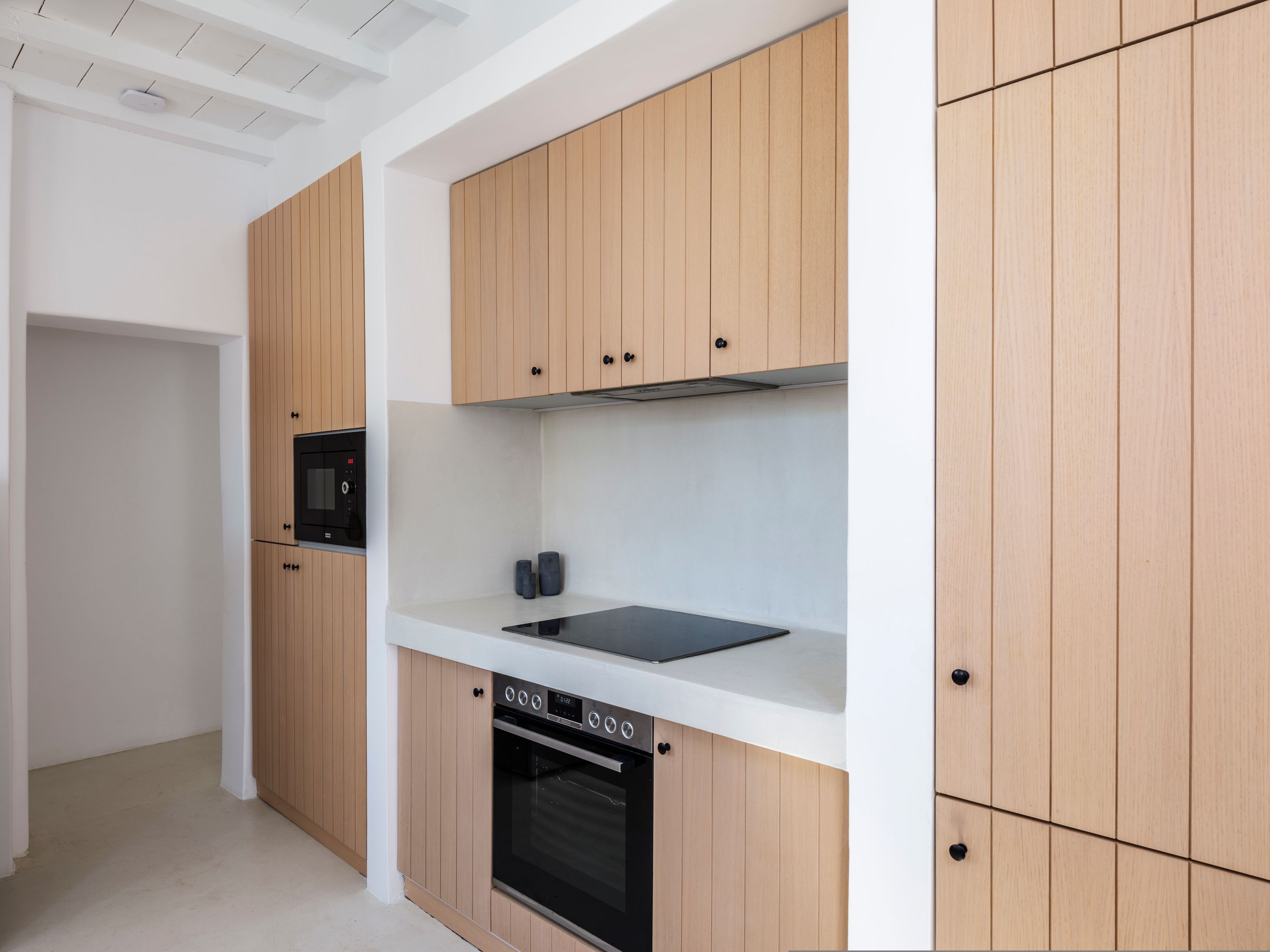 Uma cozinha moderna com armários de madeira, forno embutido e micro-ondas.
